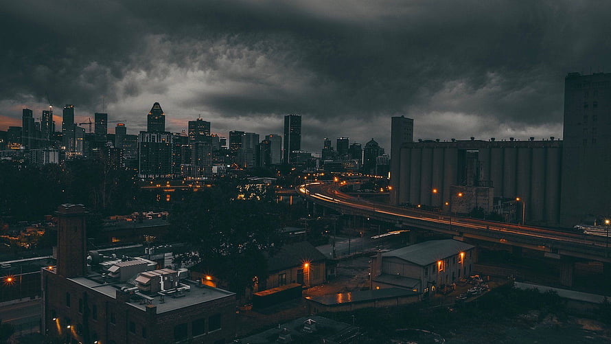 Moody Urban Skyline at Dusk with Dramatic Storm Clouds and City Lights HD wallpaper
