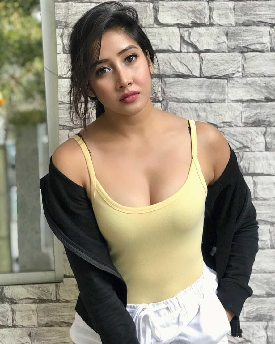 Sofia Ansari in a yellow tank top and black cardigan against a stone wall HD phone wallpaper