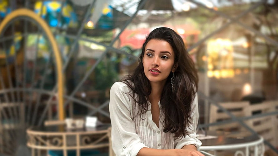 Tripti Dimri in a white blouse seated at a cafe table with a softly blurred background HD wallpaper