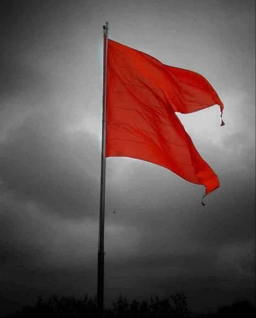 Vibrant Saffron Flag Billowing Against a Dark Stormy Sky HD phone wallpaper