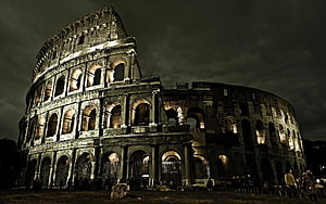 Colosseum in Rome at Night with Dramatic Dark Sky and Warm Architectural Lighting HD wallpaper