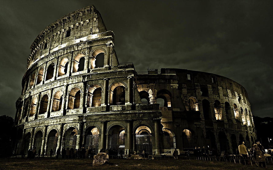 Colosseum in Rome at Night with Dramatic Dark Sky and Warm Architectural Lighting HD wallpaper