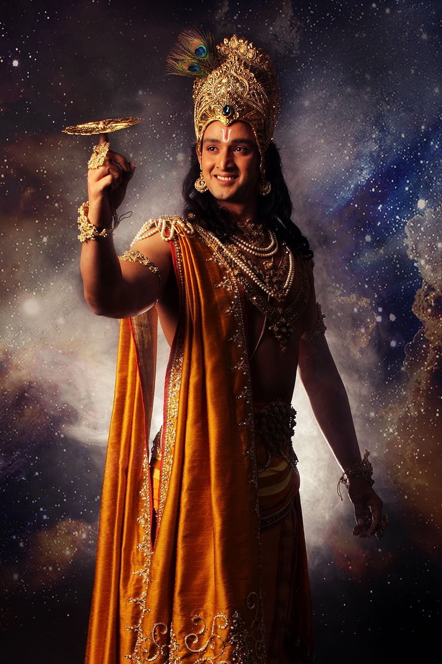 Krishna in Golden Regalia Holding a Disc Against a Cosmic Starry Sky HD phone wallpaper