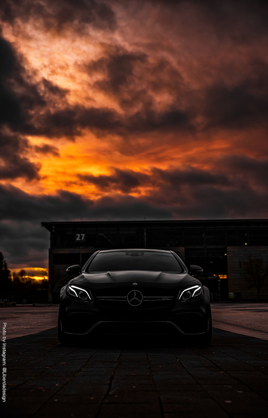 Black Mercedes-AMG E63 S Front View Under Dramatic Orange Sunset Sky HD phone wallpaper