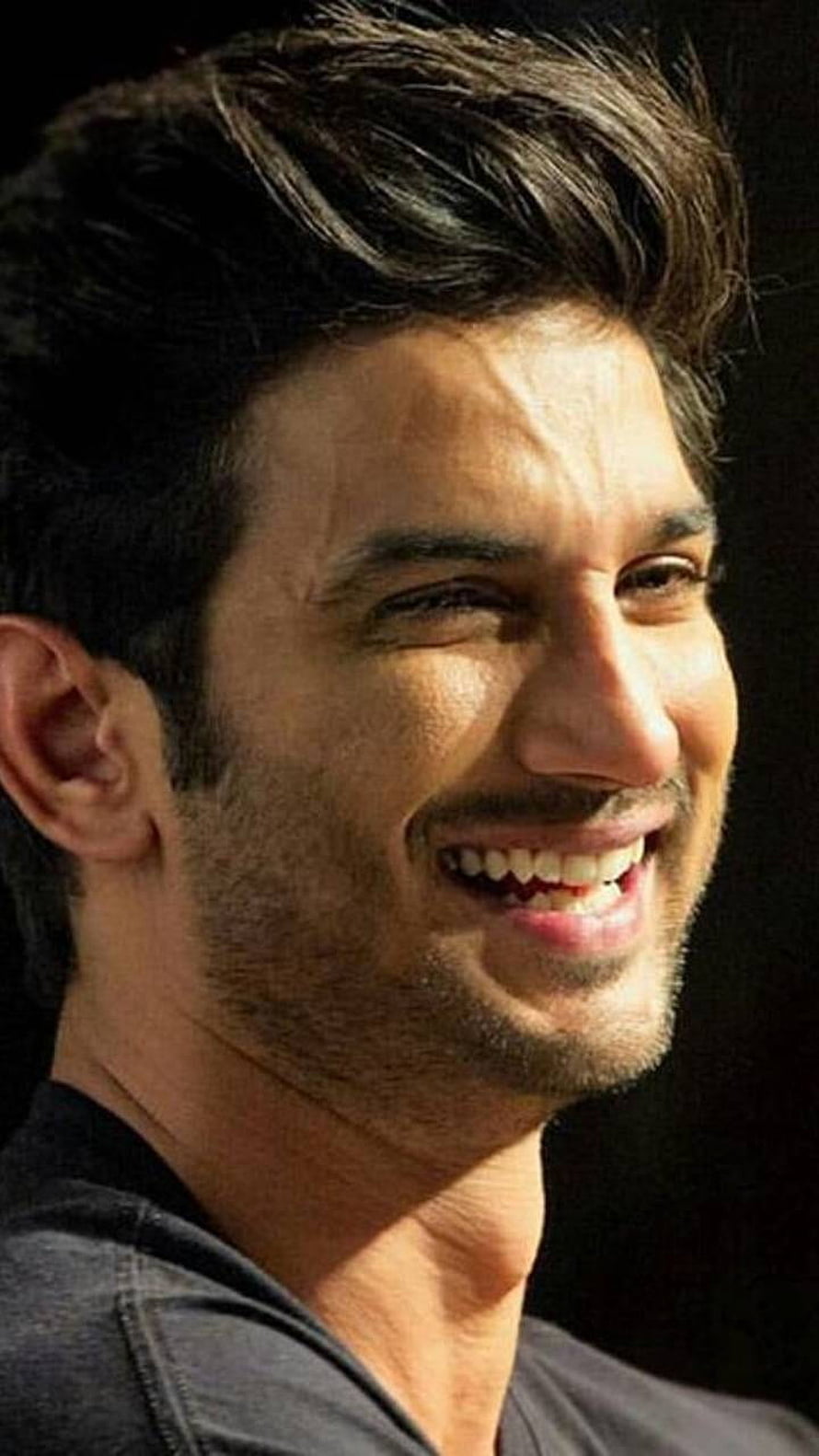 Sushant Singh Rajput smiling portrait with short dark hair and stubble against a black background HD phone wallpaper