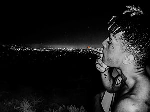 XXXTentacion smoking a cigarette overlooking a city skyline at night in black and white HD wallpaper