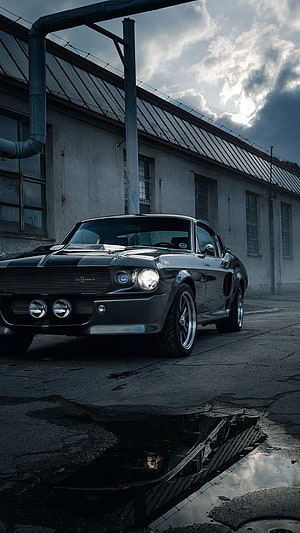 Black Ford Mustang Shelby GT500 Eleanor parked in an industrial yard under a dramatic cloudy sky HD phone wallpaper