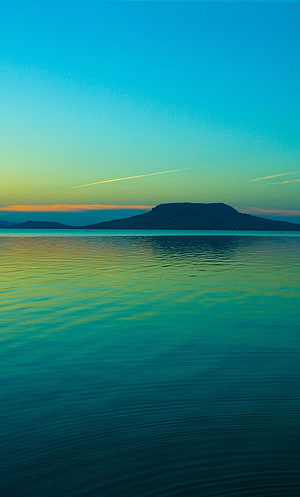 Serene Coastal Sunset with Distant Island Silhouette and Calm Turquoise Waters HD phone wallpaper