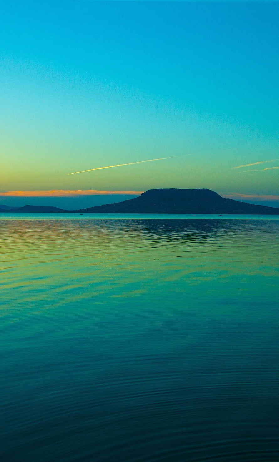 Serene Coastal Sunset with Distant Island Silhouette and Calm Turquoise Waters HD phone wallpaper