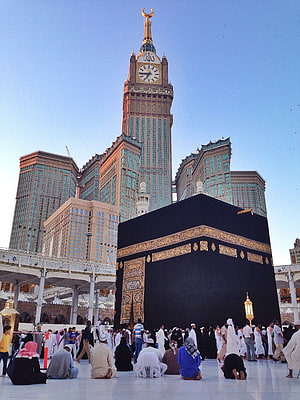 The Kaaba in Mecca with the Makkah Clock Tower and pilgrims in prayer HD phone wallpaper