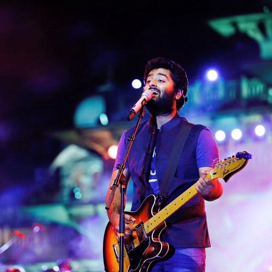 Arijit Singh performing live on stage with electric guitar and microphone under colorful concert lighting HD phone wallpaper