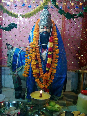 Baba Mohan Ram deity statue adorned with marigold garlands and blue robes in a temple setting HD phone wallpaper