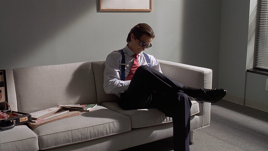 Christian Bale as Patrick Bateman in American Psycho Sitting on a Couch HD wallpaper
