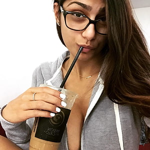 Mia Khalifa sipping iced coffee in a grey zip-up hoodie with black glasses HD phone wallpaper