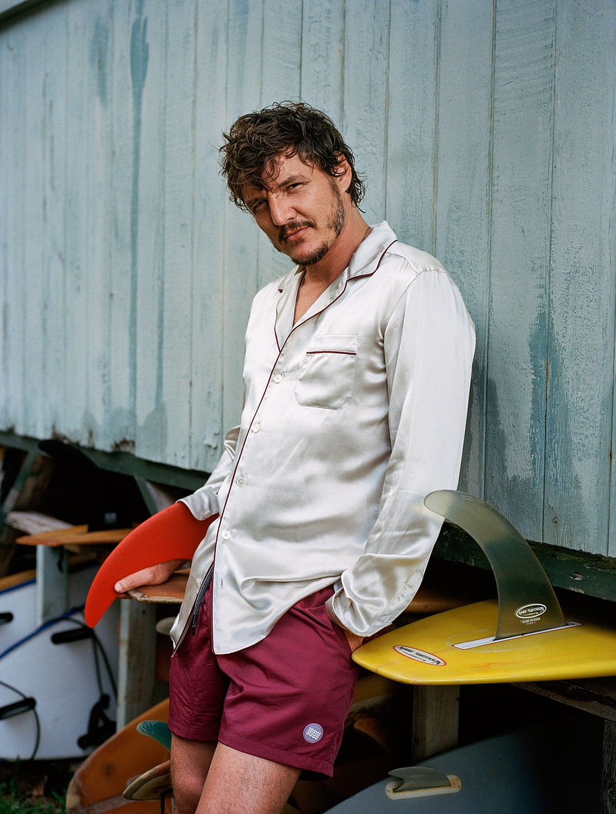 Pedro Pascal in Silk Shirt and Board Shorts Leaning Against Surfboards HD phone wallpaper