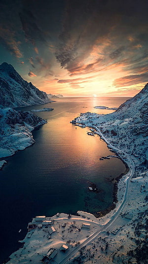 Aerial View of Snow-Covered Fjord at Golden Hour with Dramatic Clouds HD phone wallpaper