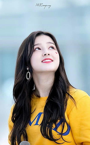 Nancy Jewel McDonie in a yellow sweatshirt with long dark hair and a soft smile HD phone wallpaper