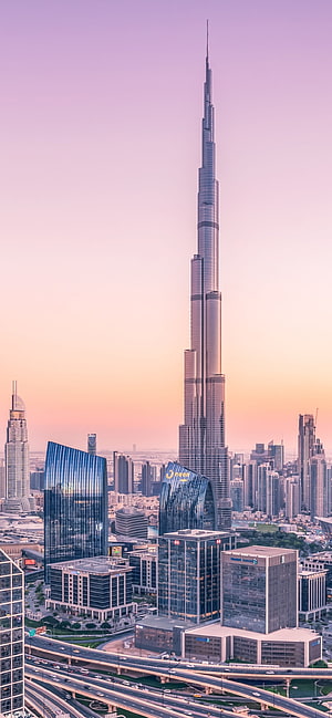 Burj Khalifa Tower Rising Over Dubai Cityscape at Sunset with Highway Interchange HD phone wallpaper