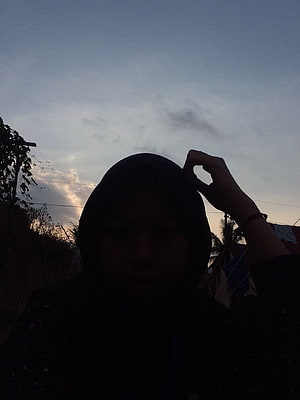 Silhouette of a woman in a hijab against a twilight sky with soft clouds HD phone wallpaper