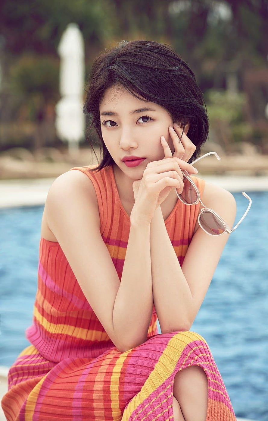 Bae Suzy in a colorful striped dress by a pool holding sunglasses HD phone wallpaper