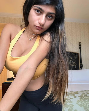 Young woman with long dark hair in yellow halter top and black leggings posing in a bedroom, Mia Khalifa by Gurusad, mia khalifa HD phone wallpaper