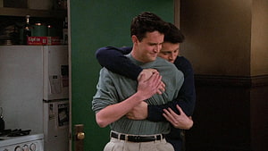 Joey and Chandler sharing a warm embrace in the Friends apartment kitchen HD wallpaper
