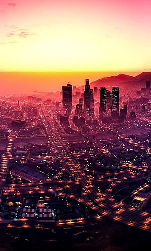GTA V City Skyline at Sunset with Glowing Highway Interchanges and Distant Mountains HD phone wallpaper
