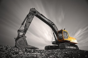 Volvo Excavator Digging Through Rocky Terrain Under Dramatic Sky HD wallpaper
