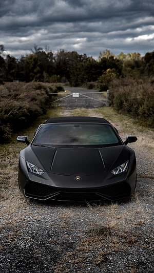 Matte Black Lamborghini Huracan Spyder Front View on Gravel Road Under Stormy Sky HD phone wallpaper