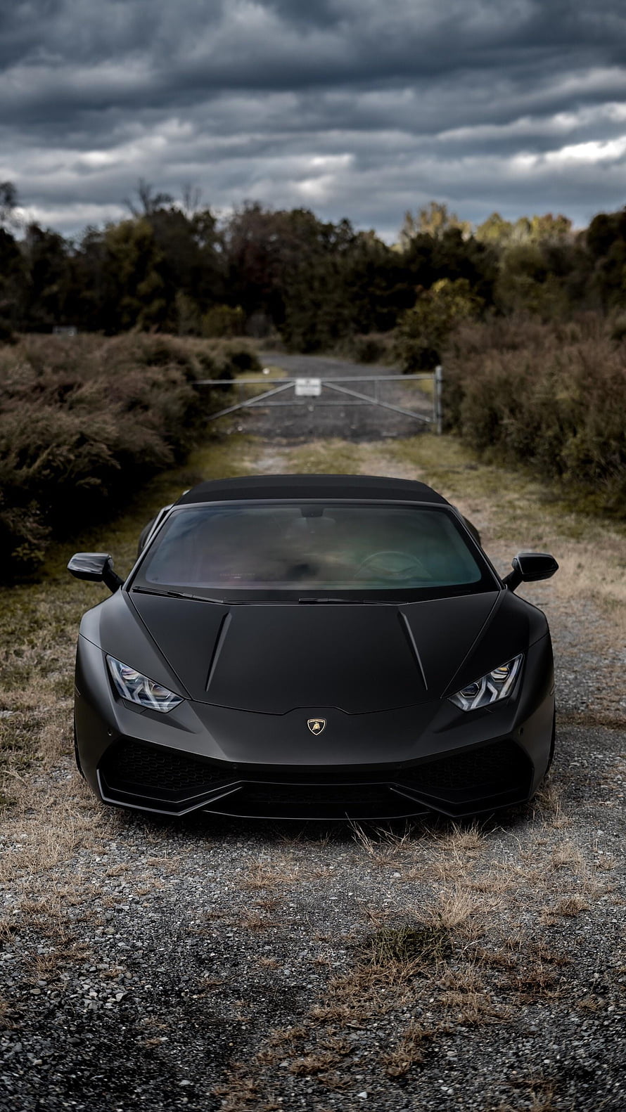 Matte Black Lamborghini Huracan Spyder Front View on Gravel Road Under Stormy Sky HD phone wallpaper
