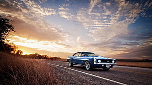 Classic Blue Muscle Car Cruising on a Country Road at Sunset HD wallpaper