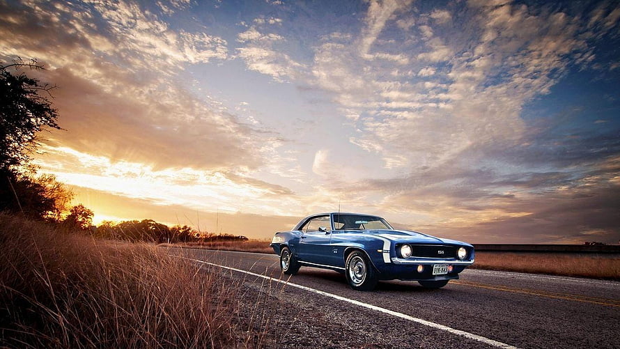 Classic Blue Muscle Car Cruising on a Country Road at Sunset HD wallpaper