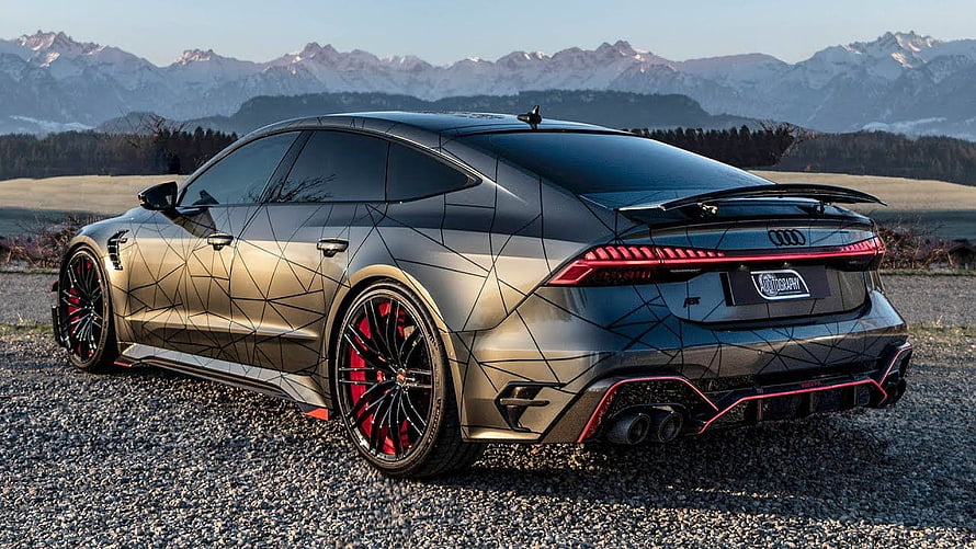 Audi RS7 Sportback with geometric livery and red brake calipers parked on gravel with mountain backdrop HD wallpaper