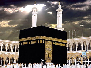 The Kaaba in Makkah with Minarets and Pilgrims Under Dramatic Sky HD wallpaper