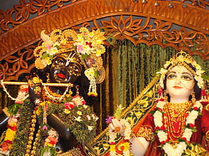 Ornate Krishna and Radha Deities Adorned with Fresh Flowers and Gold Jewelry in Temple Setting HD wallpaper