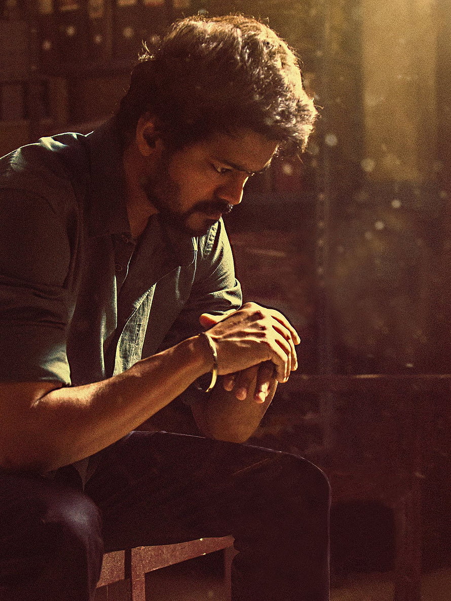 Vijay in a contemplative moment from the film Master, seated in warm cinematic lighting HD phone wallpaper