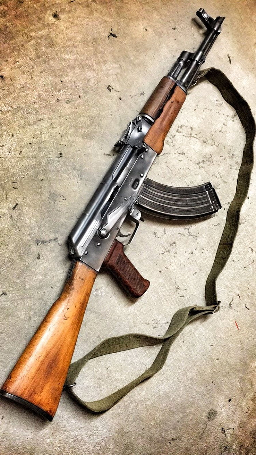 Vintage AKM Assault Rifle with Wooden Furniture and Olive Sling on Concrete Surface HD phone wallpaper