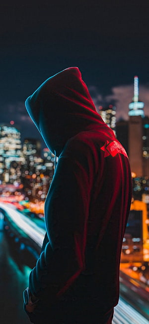Mysterious Hooded Figure Silhouette Against Vibrant City Night Skyline HD phone wallpaper