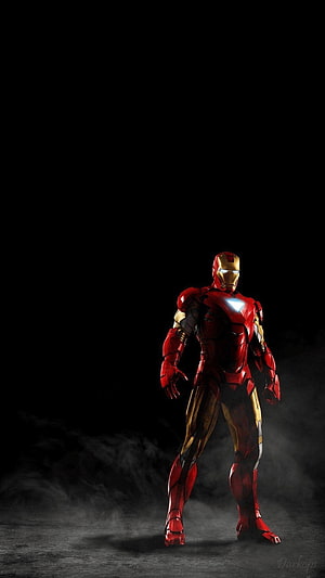 Iron Man Standing in Dark Fog with Glowing Arc Reactor and Illuminated Eyes HD phone wallpaper