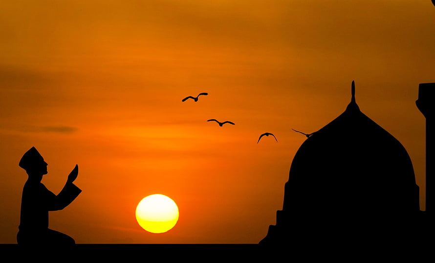 Silhouette of a Muslim man in prayer at sunset with mosque dome and birds in the sky HD wallpaper