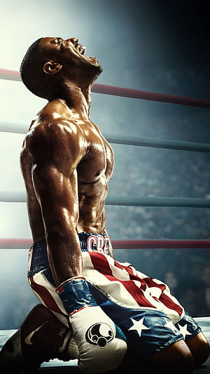 Boxer kneeling in ring with American flag trunks and head thrown back in victory HD phone wallpaper
