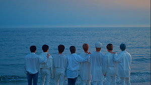 Stray Kids members standing together in white outfits facing the ocean at dusk HD wallpaper