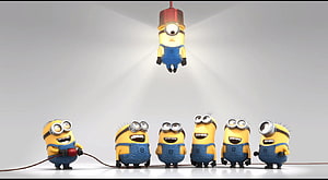 Minions characters in a spotlight scene with one hanging from a wire and others standing in a row HD wallpaper