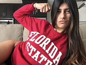Mia Khalifa in Red Florida State Sweatshirt Flexing Bicep on Beige Sofa HD wallpaper