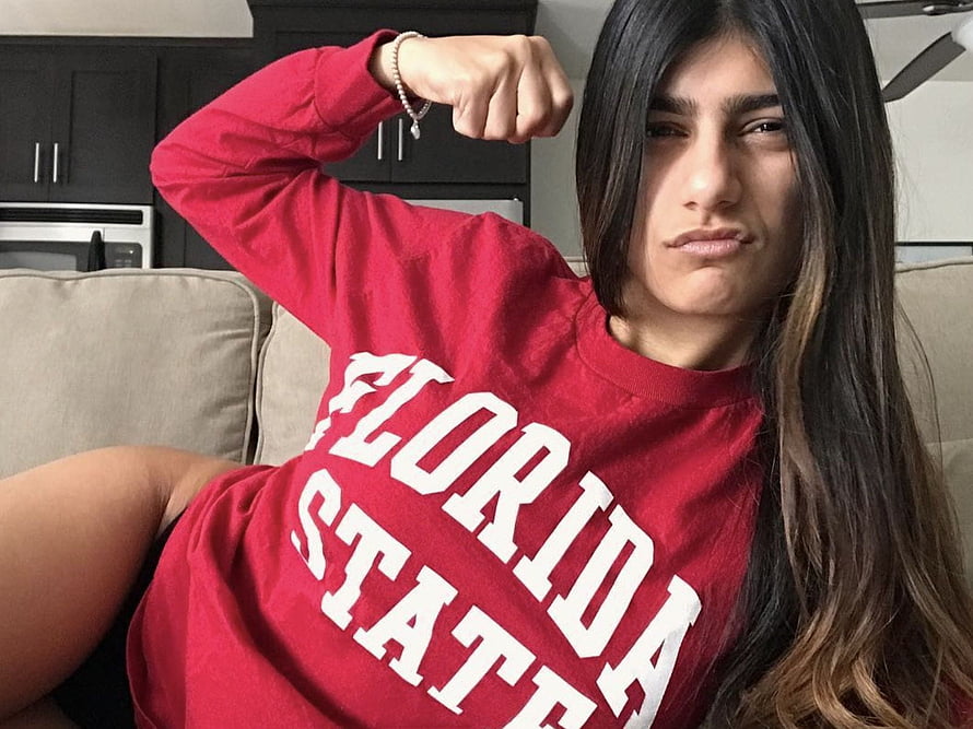 Mia Khalifa in Red Florida State Sweatshirt Flexing Bicep on Beige Sofa HD wallpaper