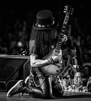 Slash from Guns N' Roses kneeling on stage with Gibson guitar in black and white HD phone wallpaper