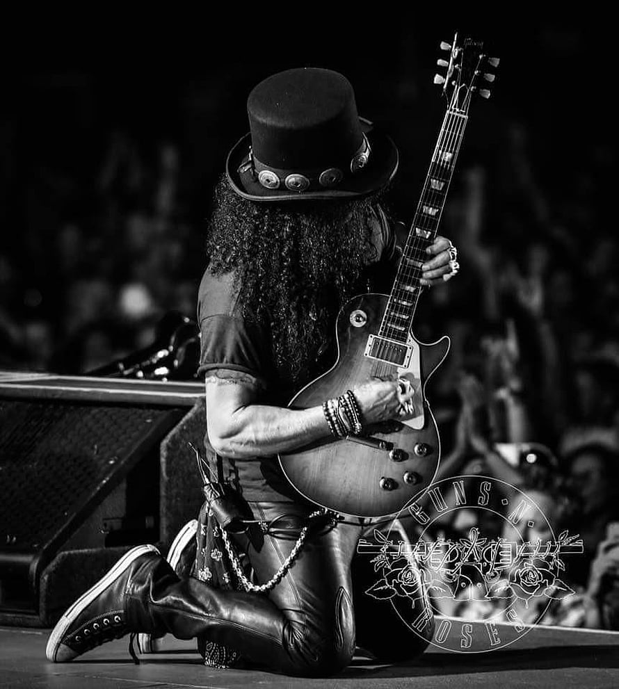 Slash from Guns N' Roses kneeling on stage with Gibson guitar in black and white HD phone wallpaper