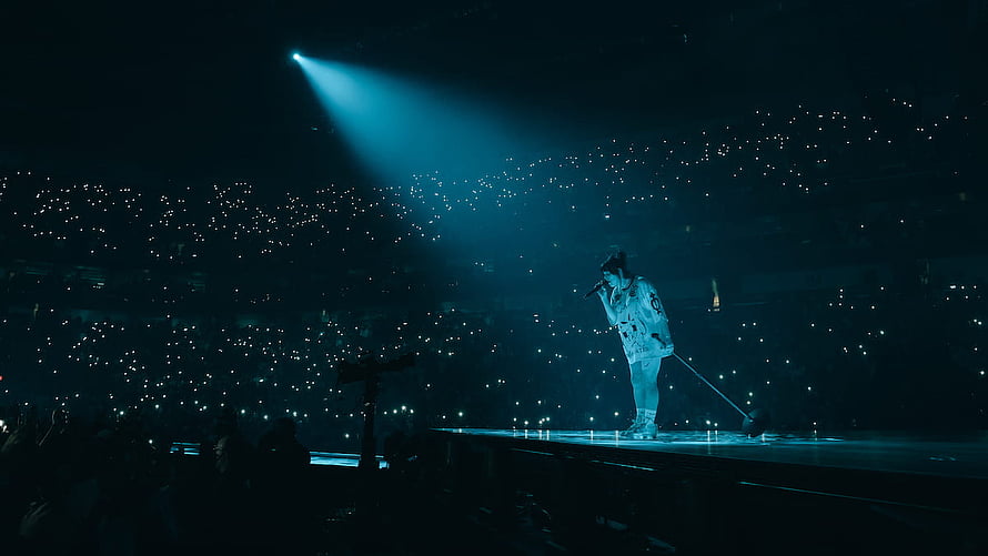 Billie Eilish performing on stage during the Happier Than Ever Tour with a sea of glowing lights HD wallpaper