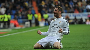 Sergio Ramos kneeling on the pitch in a white Real Madrid home kit during a match HD wallpaper