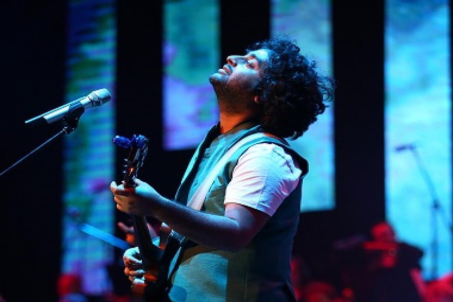 Arijit Singh performing passionately on stage with guitar under dramatic blue lighting HD wallpaper